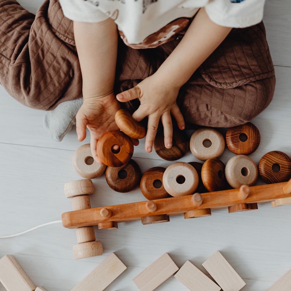 Kinderhände spielen mit Holzspielzeug